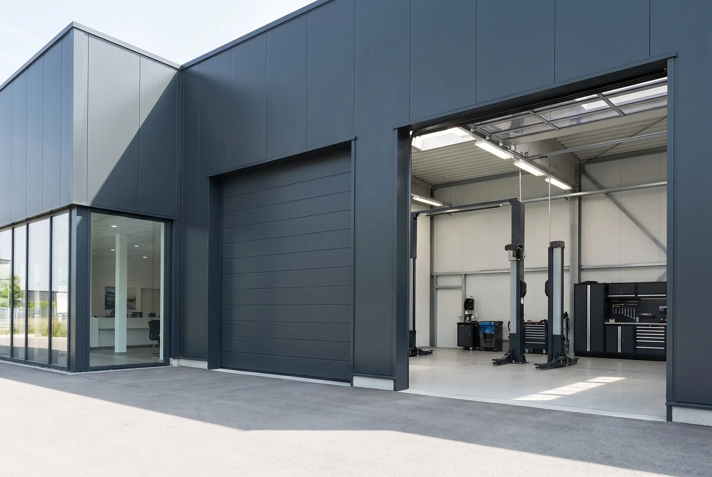 Porte sectionnelle industrielle à panneaux acier pleins sur l'atelier d'une concession automobile